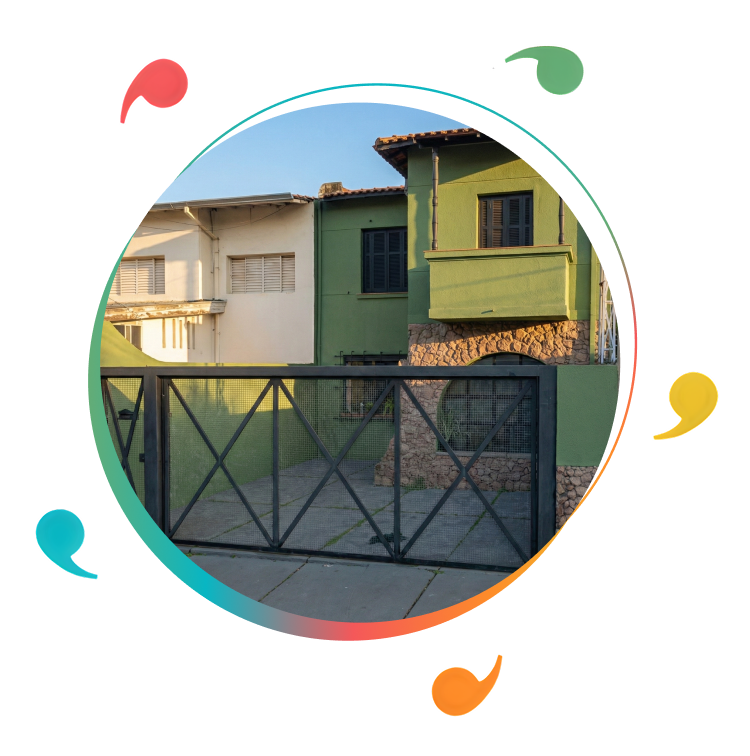 Foto da nova sede da Sociedade Amigos da Cultura (SAC), mostrando a fachada de um imóvel com portão metálico na frente e parede externa em tom verde, dentro de uma moldura circular com aro em degradê colorido e vírgulas coloridas ao redor, seguindo a identidade visual da SAC.